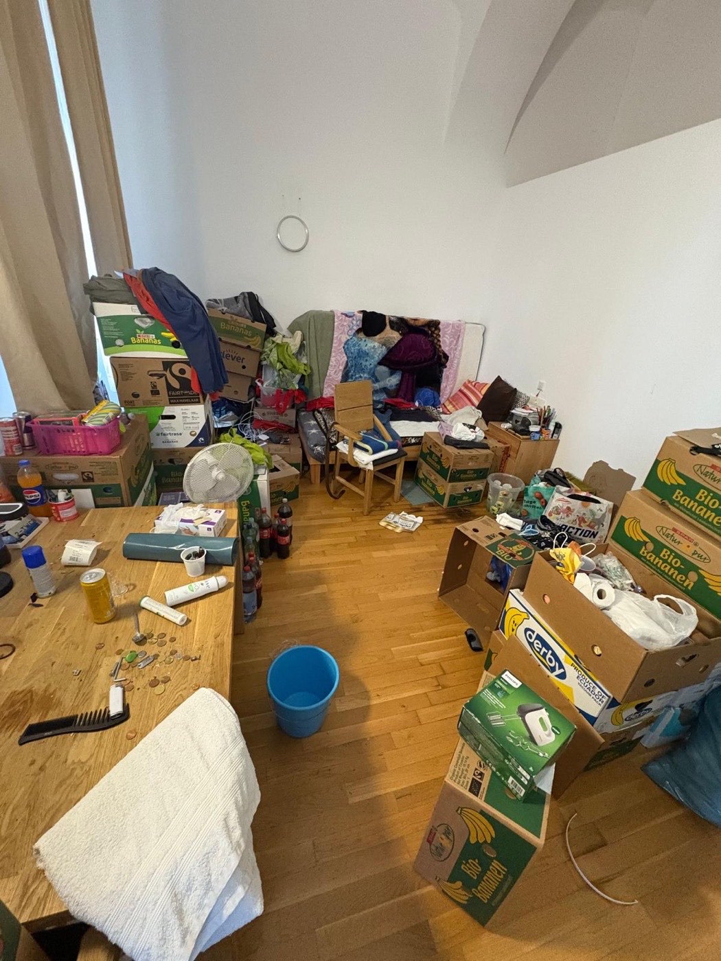Zimmer voller Kartons und Kleidung vor der Entrümpelung