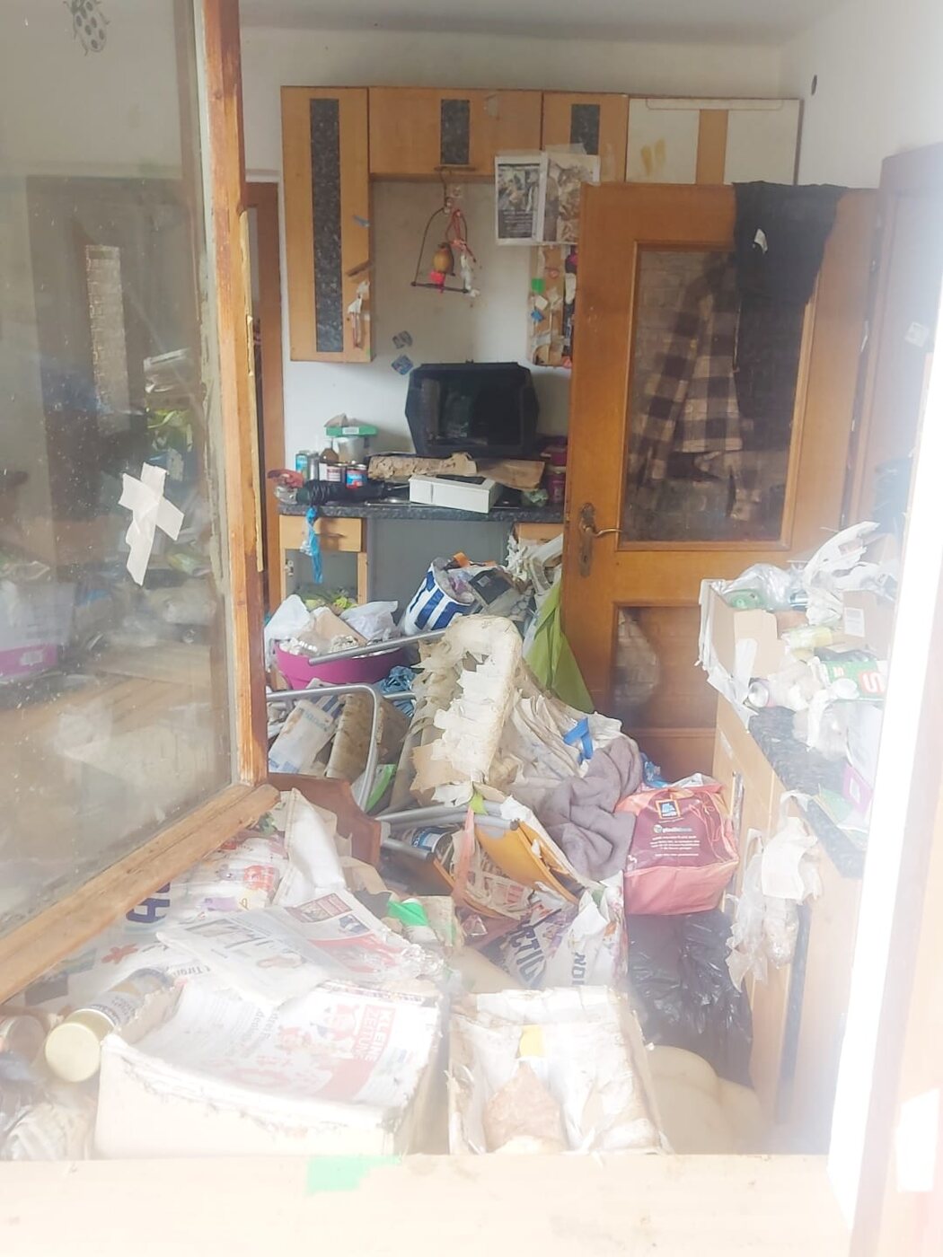 Blick durch die Glastür in ein vermülltes Zimmer