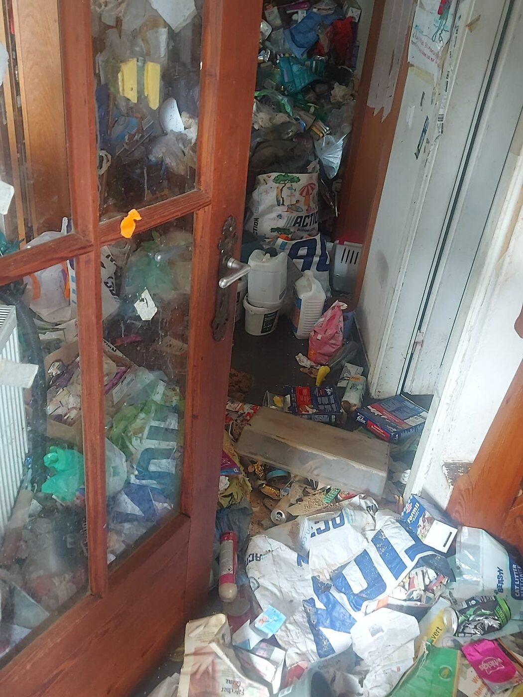 Glastür und Raum voller Plastikmüll vor der Räumung