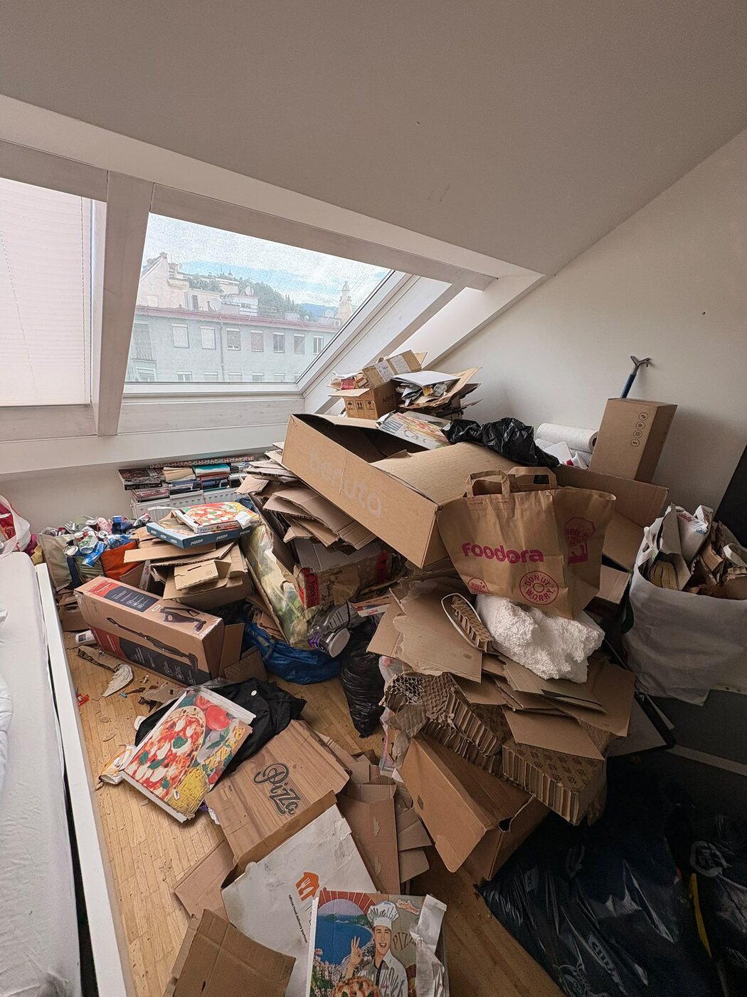 Dachzimmer mit Bergen aus Karton und Verpackungen