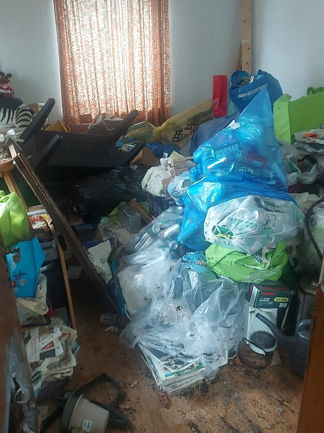 Zimmer mit gestapelten Plastiksäcken und Zeitungen