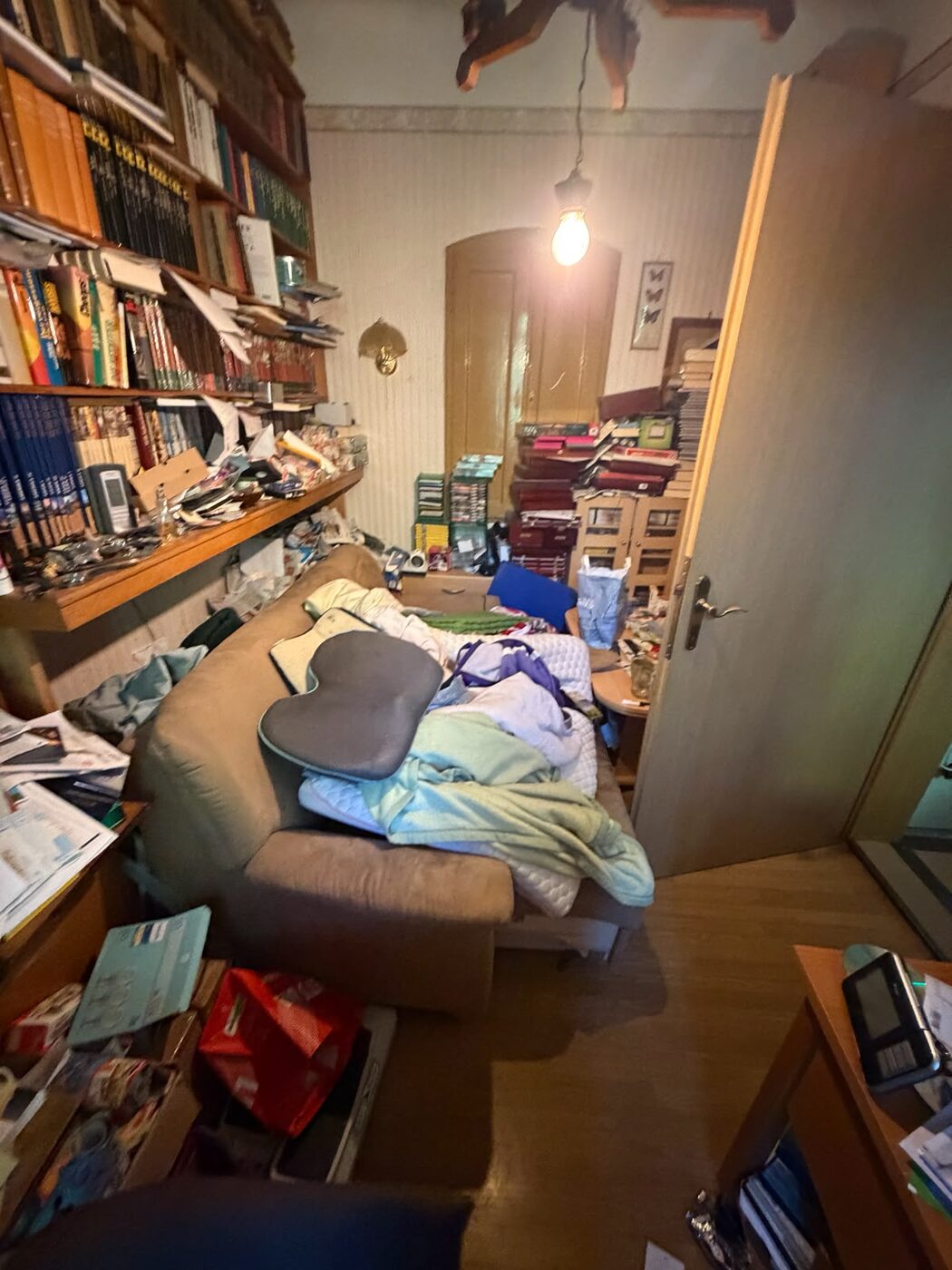 Vollgestelltes Wohnzimmer mit überfüllten Bücherregalen vor der Räumung