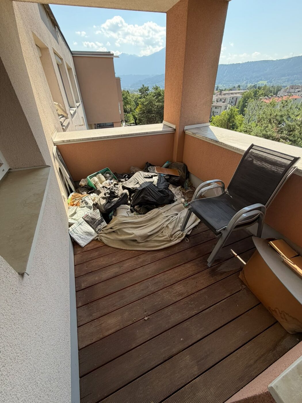 Vermüllter Balkon vor der Entrümpelung, im Hintergrund die Berge